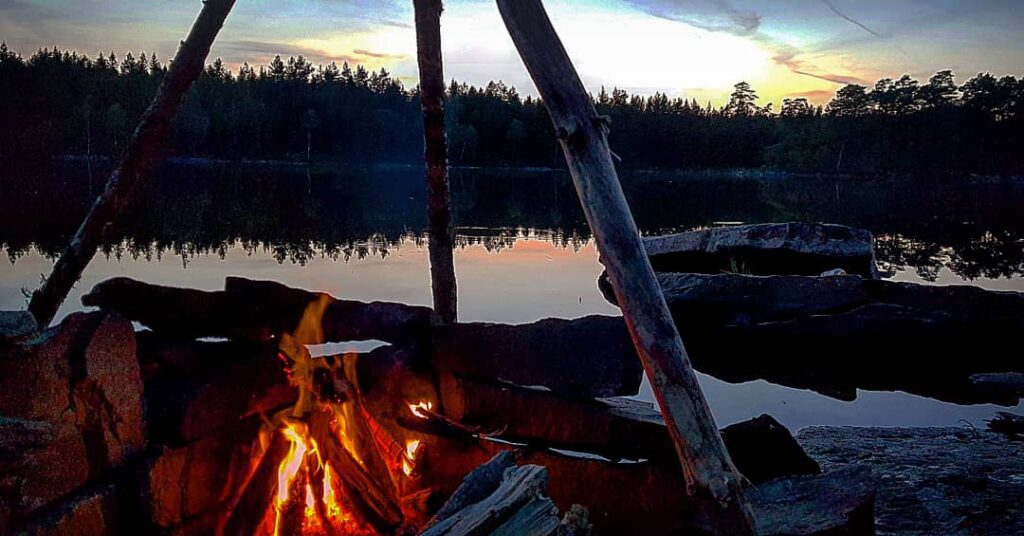 En eld vid en sjö sent på kvällen